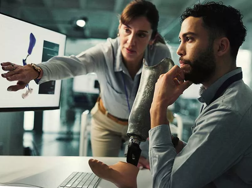 Medizintechniker am Computer mit Fußprothese