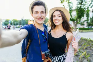 Mann und Frau machen Selfie und haben eine Landkarte in der Hand.