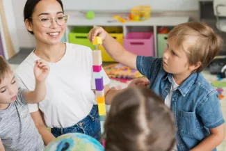 Frau mit Kindern und Stapel von Bauklötzen