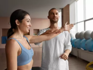 Frau bei einer Übung mit einem Physiotherapeuten.