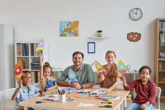 Erzieher und Kindergartenkinder basteln bunte Raketen
