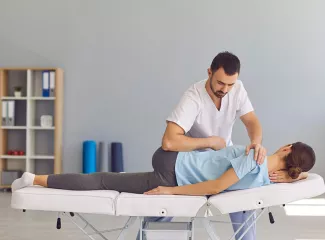 Osteopath behandelt eine Patientin in Seitenlage