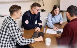 Gruppe von Rettungssanitäter:innen in der Ausbildung an einem Tisch sitzend