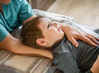 Circa vierjähriges Kind liegt auf einer Liege und wird osteopathisch behandelt.