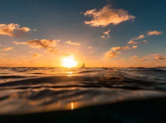 Sonnenaufgang über dem Meer mit Boot und Wellen