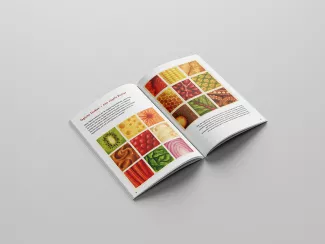 Aufgeklapptes Buch mit Bildern von Nahrungsmitteln auf hellgrauem Hintergrund