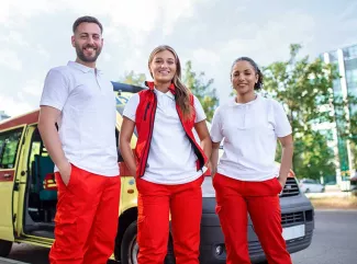 Drei Sanitäter:innen schauen in die Kamera