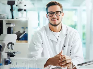 Pharmamanager am Arbeitstisch mit Mikroskop