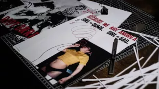 Auf einer Schneidematte liegen gestaltete Magazinseiten von Rote Nelken mit Riot-Grrrl-Motiven, Protestzitat und Werkzeugen; die Szene zeigt den analogen Entstehungsprozess eines feministischen Typografie Projekts.