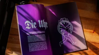 Geöffnete lila Doppelseite des Magazins mit der Überschrift Die Uhr, einer gezeichneten Uhr und einer laufenden Figur; die Szene verweist auf Zeitdruck und gesellschaftliche Machtstrukturen.