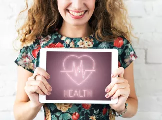 Frau hält Tablet mit Gesundheitssymbol