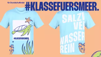 Vorder- und Rückseite eines hellblauen Kinder-T-Shirts auf pfirsichfarbenem Grund. Vorn sind eine Meeresschildkröte, ein Seestern und der Hashtag #KlassefuersMeer abgebildet; die Rückseite trägt großflächige weiße Typografie