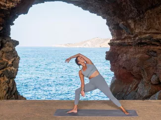 Frau macht Yoga am Meer