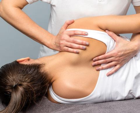 Patientin wird von einer Osteopathin an der Schulter behandelt