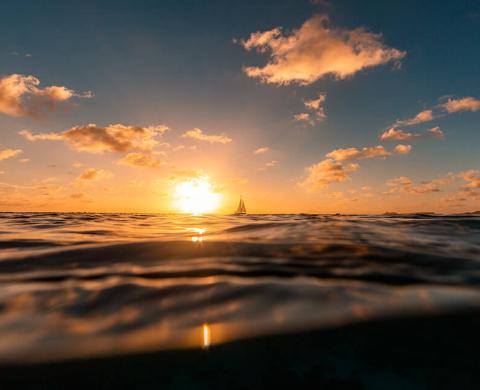Sonnenaufgang über dem Meer mit Boot und Wellen