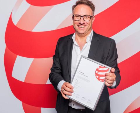 Daniel Nusser präsentiert vor einer rot-weißen Award-Kulisse seine Red-Dot-Urkunde.