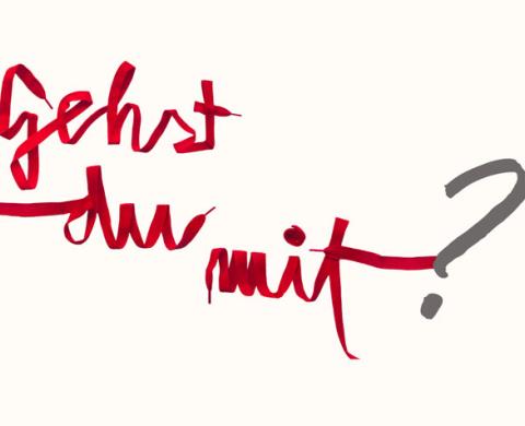 Kalligraphie „gehst du für mit Hoffnung“ auf grauem Beton-Hintergrund, rechts hervorgehoben das Wort „mit“ in roter Handschrift; am Boden weiße Fußspuren, die zum Plakat führen. Kalligraphie „gehst du für mit Hoffnung“ auf grauem Beton-Hintergrund, rechts hervorgehoben das Wort „mit“ in roter Handschrift; am Boden weiße Fußspuren, die zum Plakat führen.