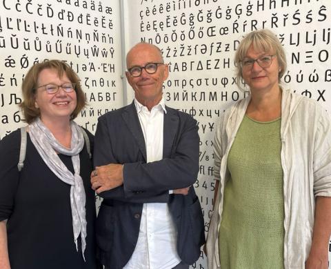 Drei Personen vor einer Wand mit typografischen Zeichen während des Besuchs der Ausstellung „Von Stadthagen in die Welt“ in Stadthagen.