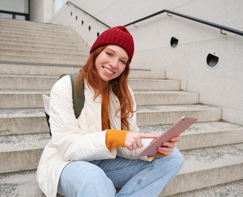 Studentin mit Tablet auf einer Treppe im Freien