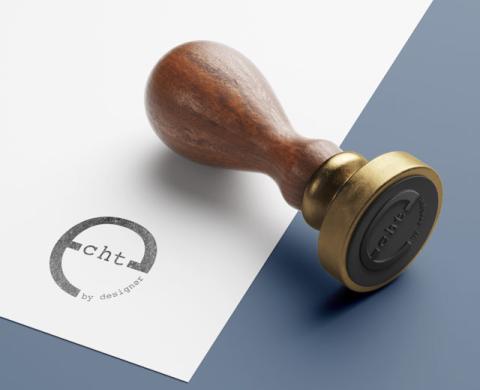 Holzstempel mit rundem Siegel auf weiß-blauem Hintergrund; der Abdruck zeigt ein Echtheitszeichen mit dem Schriftzug „echt by design“, das für menschliche Gestaltung und die bewusste Abgrenzung zu KI-generierten Inhalten steht.